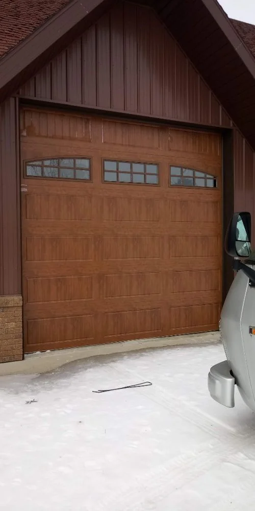 Wood-grain garage door with arched windows on barn