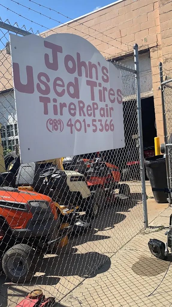 John's Used Tires sign with phone number in front of the shop
