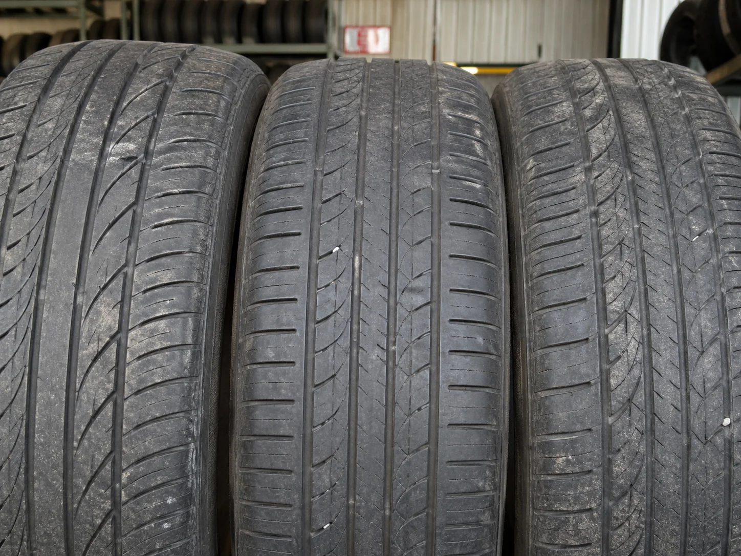 Close-up of three used tires showing tread in the tire shop